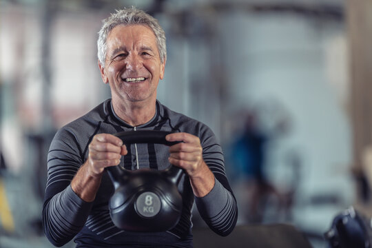 Aged but fit male lifting dumbells working out in a fitness center