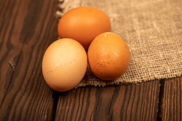 A few yellow, large chicken eggs on a background of homespun fabric with a rough texture. Close-up, selective focus.