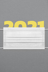 Colors of the year - PANTONE 17-5104 Ultimate Gray and 13-0647 Illuminating. Figure 2021 under a medical mask on a dark paper textured background.