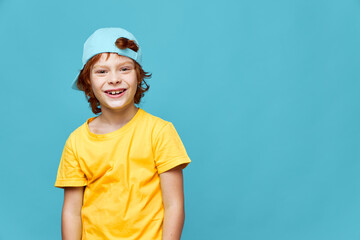 Cheerful boy red hair blue cap on his head yellow t-shirt Copy Space