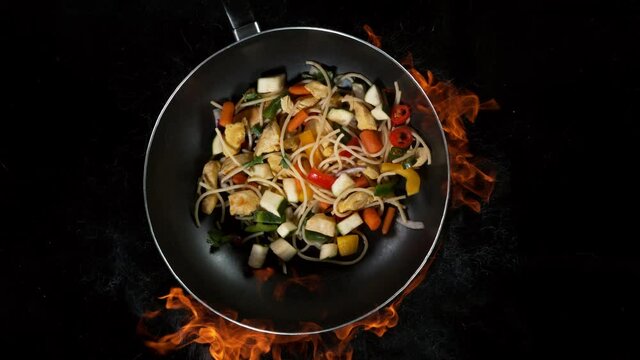 Super slow motion of flying asian chicken noodles with vegetable from pan. Filmed on high speed cinema camera, 1000 fps.