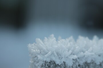 Snow crystals on the surface of a wooden column close-up