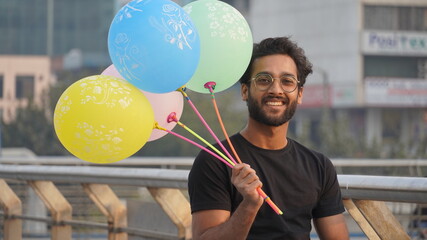 Fototapeta premium Happy Man Portrait - Outdoor, Young Indian Bearded Man Standing Outdoor with Colorful Balloons Very Happy