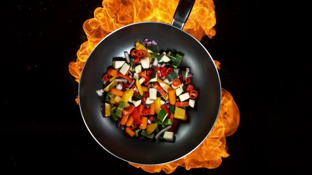 Super slow motion of flying sliced vegetable pieces from wok pan with fire. Filmed on high speed cinema camera, 1000 fps.