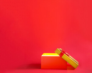 Open red gift box with a bow with a golden glow and glitter inside on a red background, banner, copyspace. universal holiday, christmas, valentine's day, new year, birthday, anniversary, present