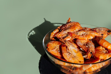 Shrimps in a transparent bowl on an olive background.  King prawns on an olive-gray background.