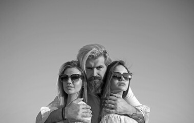 Portrait of happy man between two girls standing on sky background on summer vacation.