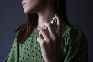 Woman applying perfume on her neck. Close up of a woman's hand applying perfume with dark background