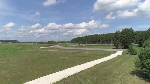 Aerial view of highway with cars. Nearby forests and fields. Nearby is a plot for the construction of an industrial facility with convenient access to the highway. Summer sunny day
