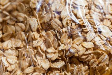 Packed rolled oats inside a plastic bag container surface macro, surface closeup, dry wholegrain healthy fit food products industry concept, nobody, abstract background texture, full frame, up close