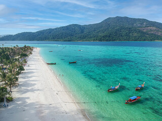 A top view over Koh Lipe island with crystal clear water with many long-tail boats. 