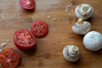 Cutting board knife and vegetables in the kitchen. Sliced tomatoes and mushrooms on a cutting Board. Mushrooms on a cutting Board