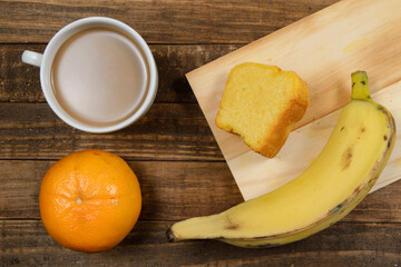 Brazilian breakfast with coffee with milk, corn cake, watermelon and orange fruit