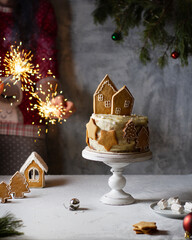 New Year's cake on a stand with gingerbread, houses, stars and Christmas trees, hands are holding sparklers