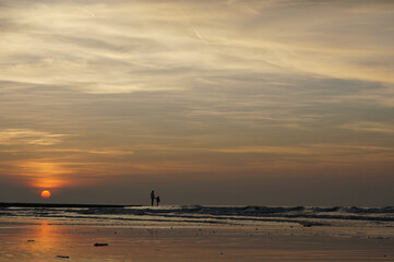 Père et fille sur une plage au coucher de soleil en Belgique