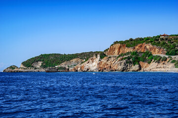 Fototapeta na wymiar Boat trip on the background of the rocky coast of Alanya (Turkey). Seascape with views of stone coastline and blue sea water