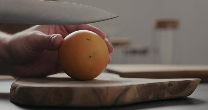 Slow motion man cut lulo fruit on olive wood board with copy space