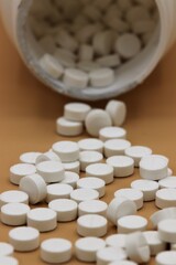 White pills spilling out of container towards camera