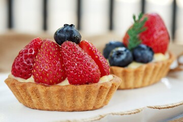 The strawberry and blueberry tarts on white dish.