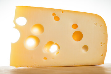 Yellow cow's milk Swiss cheese emmenthal with holes on wooden board..