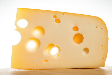 Yellow cow's milk Swiss cheese emmenthal with holes on wooden board..