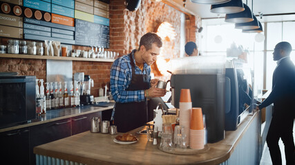 Handsome Male Barista in Checkered Shirt is Making a Latte for a Customer in a Coffee Shop Bar. Beautiful Caucasian Male Cashier Works at a Cozy Loft-Style Cafe Counter in the Background.