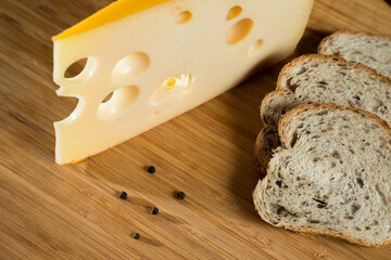 Yellow cow's milk Swiss cheese emmenthal with holes on wooden board..