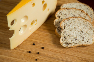 Yellow cow's milk Swiss cheese emmenthal with holes on wooden board..