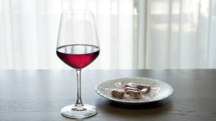 テーブルに置かれたグラスの赤ワインと付け合わせのスモークチーズ