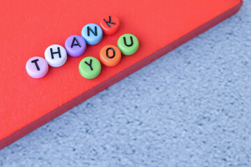 Selective focus of wooden blocks and colorful alphabet beads with text THANK YOU over grey background. 