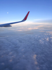 Obraz premium Airplane wing through the clouds in the sky.