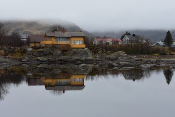 landscape of villages reflection on the lake with white fog in raining day at lofoten island norway.The rorbuer reflectionin the lake