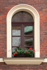 Fototapeta na wymiar red flowers on window in a old brick house