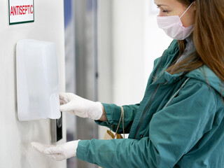 Hands using automatic sanitizer dispenser at supermarket. Disinfectant in a shopping mall during...