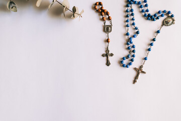 Two rosaries to pray on a white background, one small brown and the other large blue. Copy space