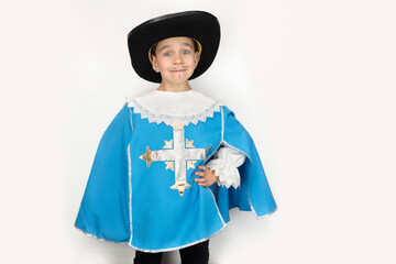 A young boy in a carnival blue musketeer costume and a black hat on a light background, the boy is...