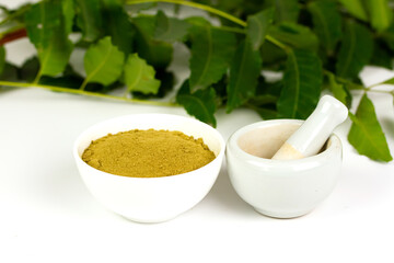 neem powder in white bowl with white mortar and pestle and neem leaf isolated on white background.
