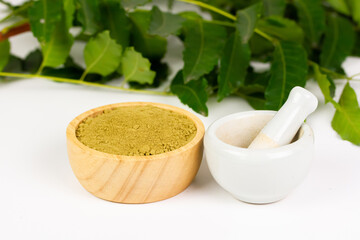 neem powder in wooden bowl with white mortar and pestle and neem leaf isolated on white background.