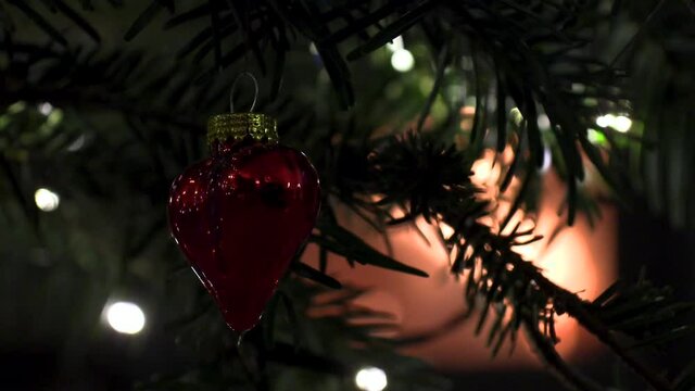 Red Heart on christmas tree with lights and fireplace in the background