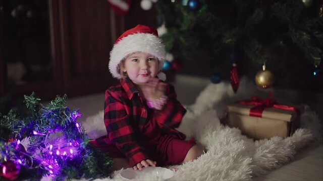 a child in red clothes is sitting waiting for the new year. the concept of celebrating Christmas at midnight. holiday costume