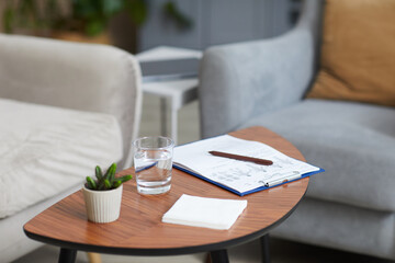Image of table with documents plant and glass of water on it in the room