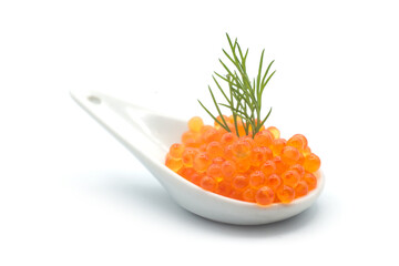 Closeup of trout roe in a ceramic spoon with a dill leaf on white background