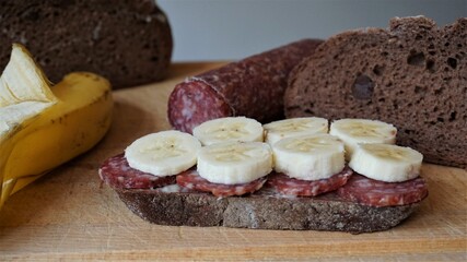 Scheibe Brot mit Salami und Bananenscheiben, Mettwurst und Obst auf dem Brot