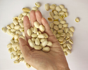 Pistachio nuts and woman's hands. Pistachios isolated on white background, top view. 