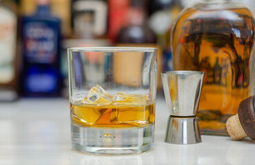 Old fashioned glass with scotch whisky and ice cubes on the bar