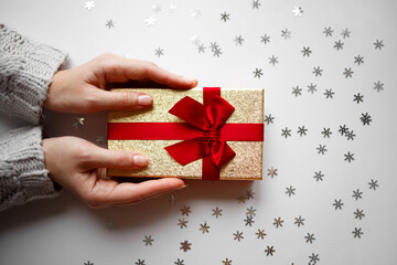 hands hold a gift on a white background with silver snowflakes