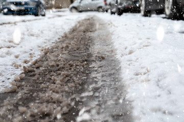 Snowy and difficult roads after snowfall in winter. Muddy tire print in snow, blurry cars in background
