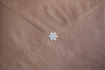 Fototapeta na wymiar Kraft paper envelope. Handmade miniature polymer clay snowflake.