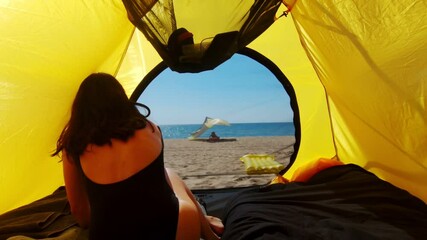 woman going out from camping tent taking inflatable mattress and running into sea