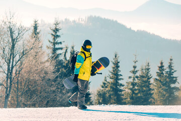 man walking by hill with snowboard